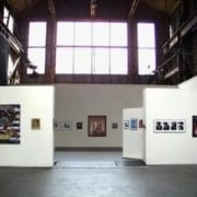 Wide angle image of a gallery with white walls and photographs