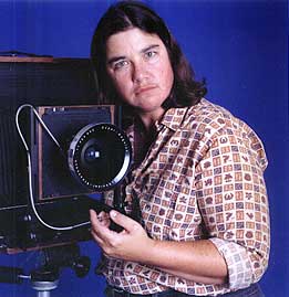 Photo of a brown haired light skinned person next to a 16x20" camera