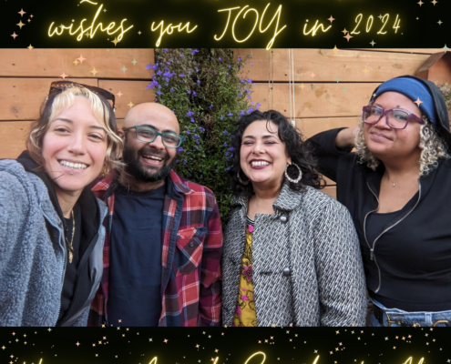 qcc staff stand in a row, smiling. left to right are vienna, anand, sarah, and ali. bright sparkly gold text reads "queer cultural center wishes you JOY in 2024" on top, with staff names at the bottom