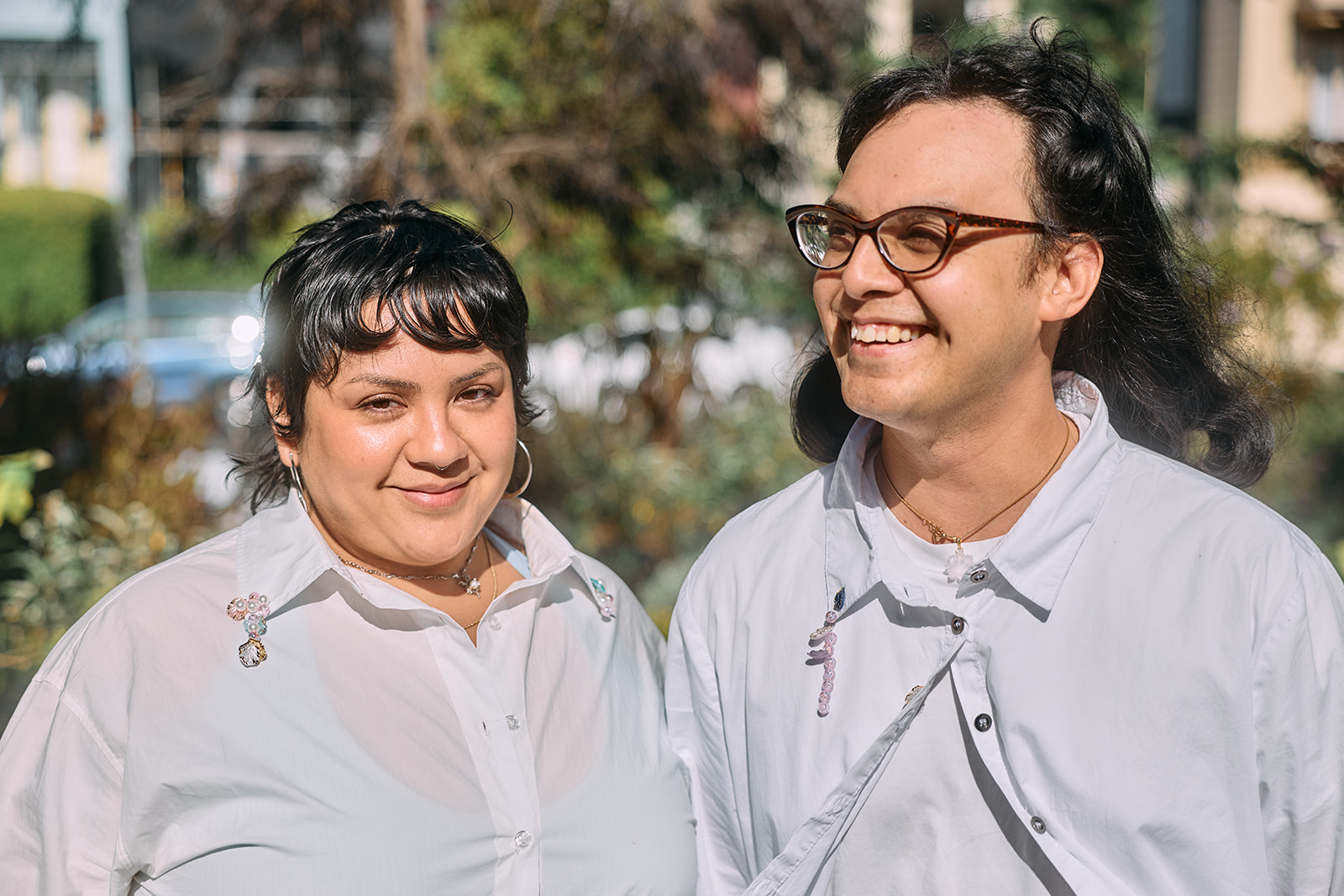 Two queer artists standing together outdoors.