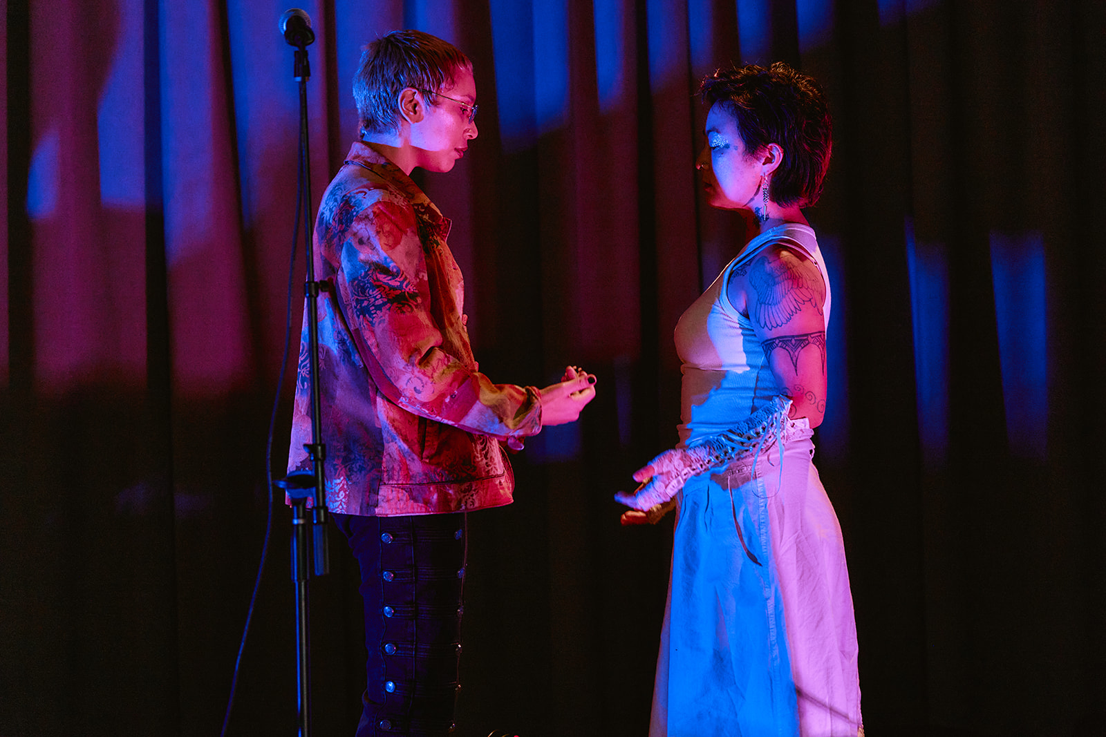 Two artists performing together under red and blue stage lighting.